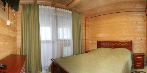 a bedroom with a bed in a room with a window at Schale Centoriya in Mykulychyn