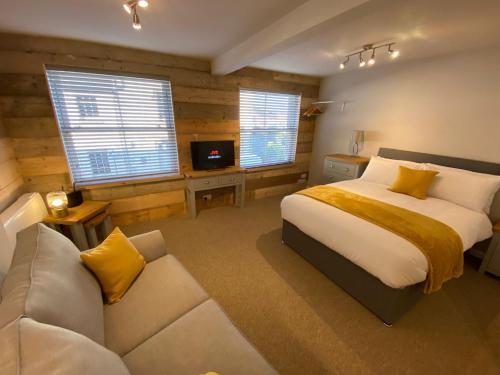 een slaapkamer met een bed, een bank en ramen bij Studio at Bastion Mews in Hereford