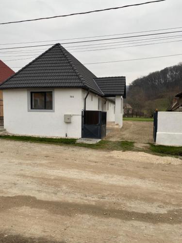 een wit huis met een zwart dak op een onverharde weg bij Casa Transilvania in Mediaş