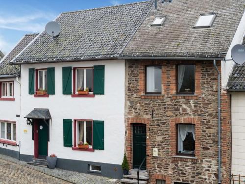 a white house with green shutters on a street at Reifferscheid Wellness Escape in Hellenthal