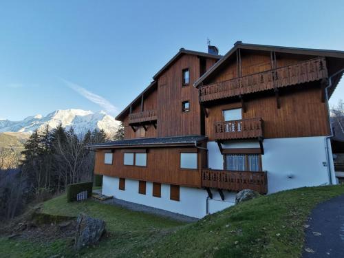 una casa en una colina con montañas en el fondo en Saint-Gervais-les-Bains, Appartement 4 personnes, en Saint-Gervais-les-Bains