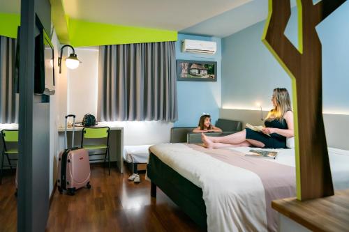 two women sitting on a bed in a hotel room at ibis Styles Curitiba Centro Civico in Curitiba