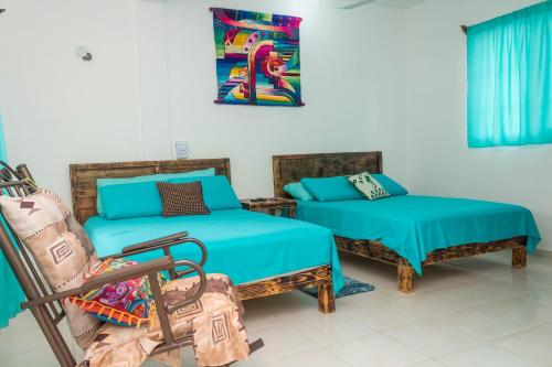 a room with two beds and a chair in it at Hotel Henry Bacalar in Bacalar