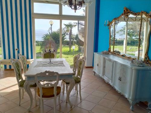 a dining room with a table and a mirror at Villa sullo stretto in SantʼAgata