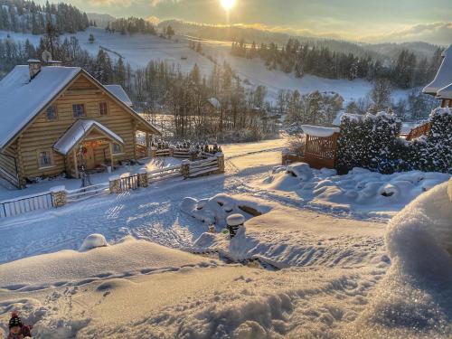 a log cabin in the snow with the sun in the background at Dziejba Leśna Apartamenty &Spa - piękne i nowe apartamenty i domek, sauna i jacuzzi - W CENIE I NA WYLACZNOŚĆ, 1 km od stoku in Jaworki
