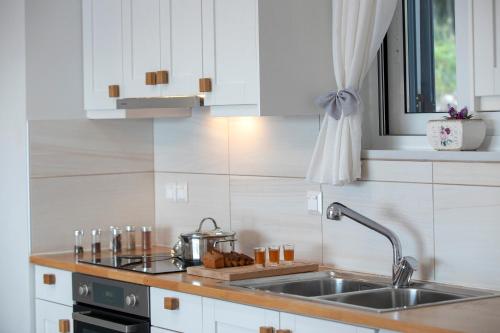 a kitchen with white cabinets and a sink at Kavos House in Spartokhórion