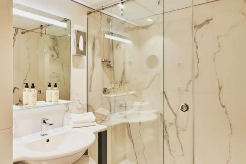 bagno bianco con lavandino e doccia di Best Western Alexandra a Saint Malo