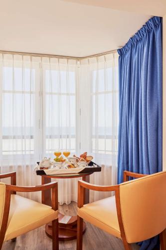 サン・マロにあるベストウエスタン アレクサンドラのダイニングルーム(テーブル、青いカーテン付)