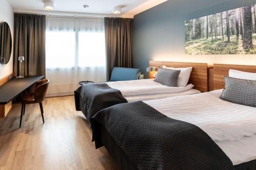 a hotel room with two beds and a desk at Scandic Espoo in Espoo