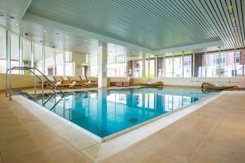 ein großer Pool in einem großen Zimmer mit Fenstern in der Unterkunft Radisson Blu Senator Hotel, Lübeck in Lübeck