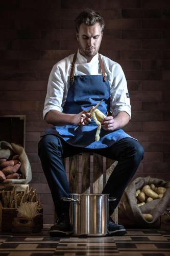 a man in an apron holding a bunch of food at Radisson Blu Hotel, Antwerp City Centre in Antwerp