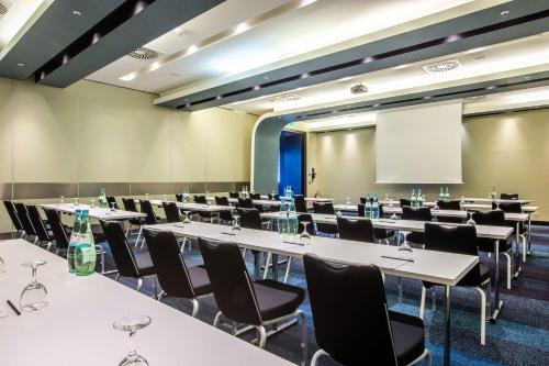 a conference room with tables and chairs and a screen at Radisson Blu Hotel, Hamburg in Hamburg