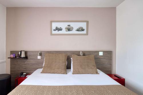 a bedroom with a white bed with two pillows at Sure Hotel by Best Western Nantes Saint-Herblain in Saint-Herblain