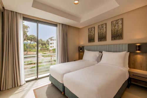 una camera con un grande letto e una grande finestra di Radisson Blu Residences Al Hoceima ad Al-Ḥoseyma