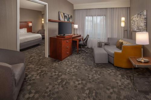 um quarto de hotel com um sofá e uma secretária com uma televisão em Sonesta Select Newark Christiana Mall em Newark
