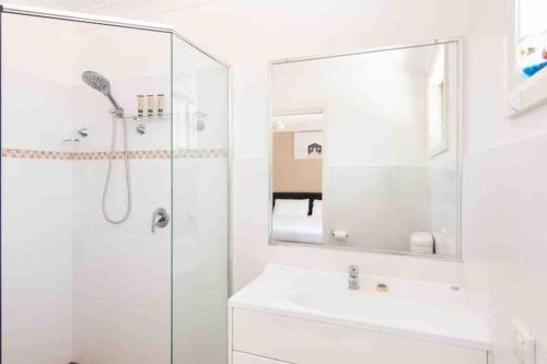 a white bathroom with a shower and a sink at 4 Bedroom modern house opposite Wallis Lake in Forster