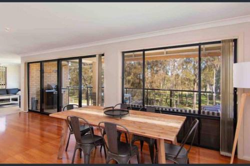 a dining room with a wooden table and chairs at 4 Bedroom modern house opposite Wallis Lake in Forster