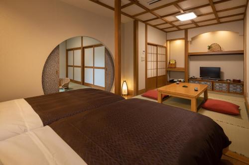 a bedroom with a large bed and a table at Yamabiko Ryokan in Minamioguni