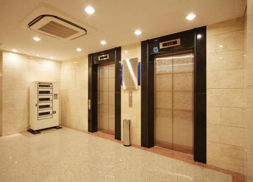 a elevator lobby with two elevators in a building at Smile Hotel Nara in Nara