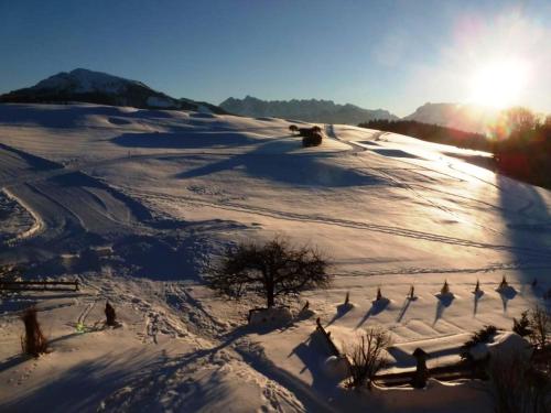 a snow covered hill with the sun in the background at Stoibhof Familie Klauser in Reit im Winkl