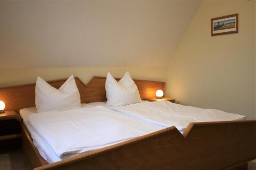 a large bed with white sheets and pillows at Dwarslöper in Am Schwarzen Busch