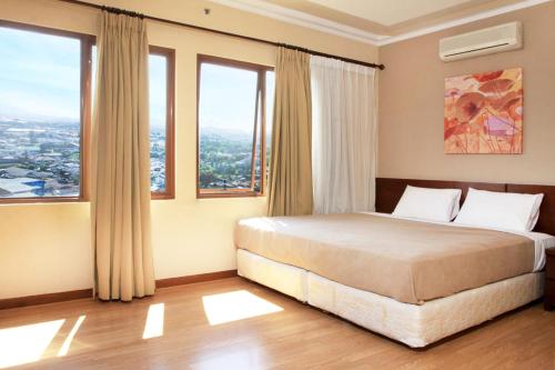 a bedroom with a bed with large windows at Daily Home Apartment in Bandung