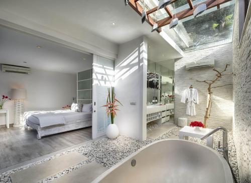 a bathroom with a tub and a bed in a room at Pure Villa Bali by Nagisa Bali in Dalung