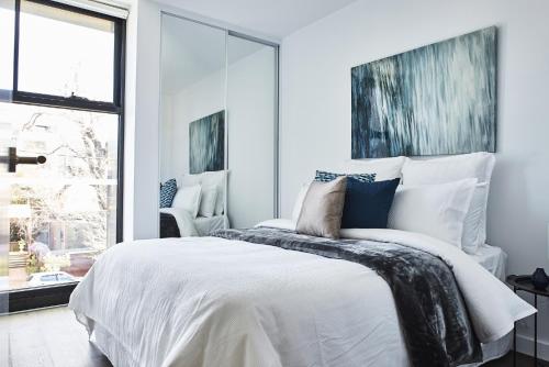 a bedroom with a bed with white sheets and blue pillows at Mega Style Apartments St Kilda in Melbourne