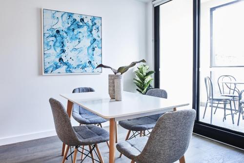 墨尔本Mega Style Apartments St Kilda的一间有白色桌子和椅子的餐厅