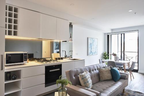a living room with a couch and a kitchen at Mega Style Apartments St Kilda in Melbourne