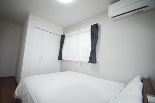 a bedroom with a white bed and a window at Plage Garden Place A-111 in Miyako Island
