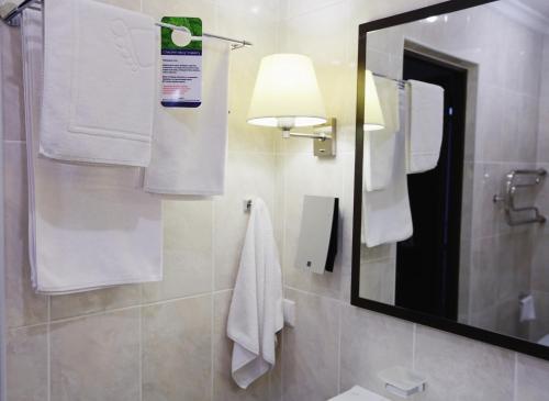 a bathroom with a mirror and white towels at Hotel Home Parq in Ekibastuz