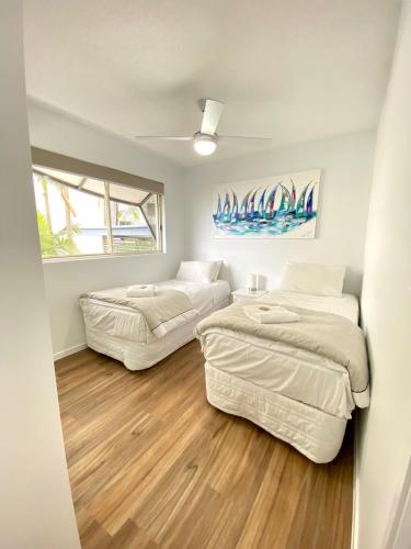 two beds in a small room with wood floors at Excellsior Apartments in Mooloolaba