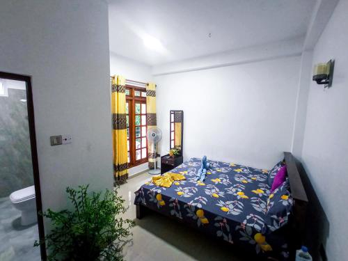 a bedroom with a bed with a blue comforter at Daffodils Inn in Adams Peak