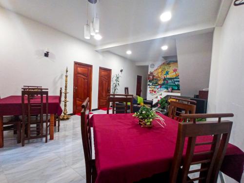 uma sala de jantar com uma mesa vermelha e cadeiras em Daffodils Inn em Nallathanniya
