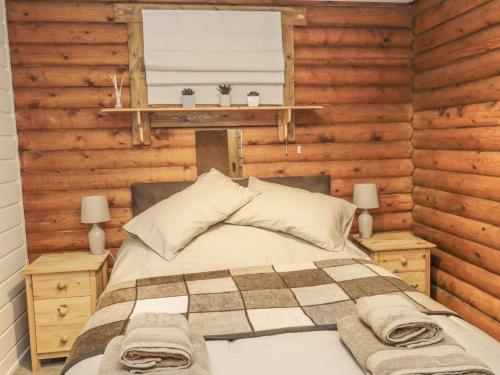 a bed in a room with wooden walls and a window at Ingram in Morpeth
