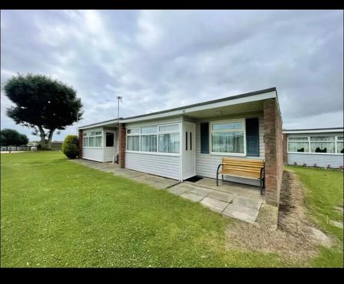 a house with a bench in front of it at Chalet hemsby in Great Yarmouth