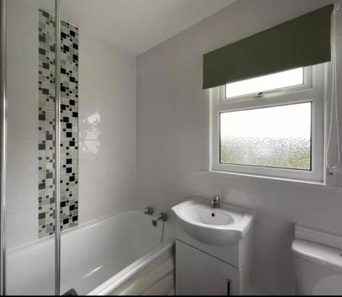 baño blanco con lavabo y ventana en Chalet hemsby en Great Yarmouth