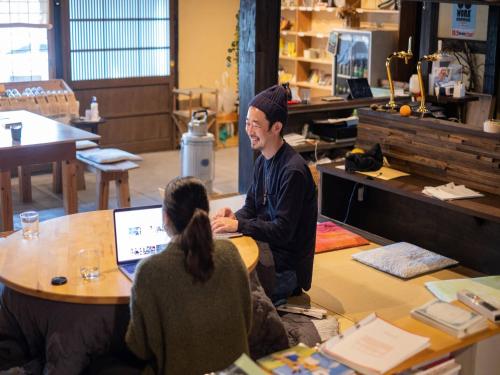 a man and woman sitting at a table in a store at Hostel & Tatami Bar Uchikobare -内子晴れ- in Uchiko