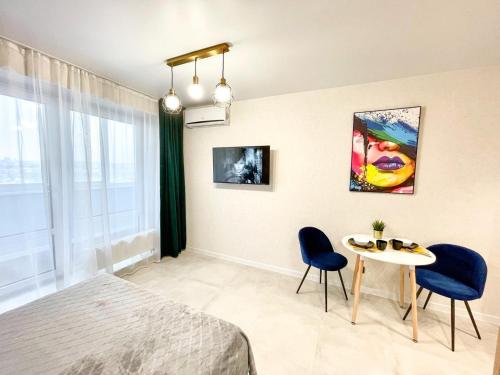 1 dormitorio con 1 cama, 1 mesa y 2 sillas en Апартаменты с видом на Лес и Реку, en Barnaul