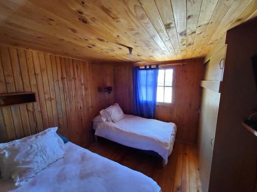 a bedroom with two beds in a wooden room at Cabañas Paraiso in Bahia Inglesa