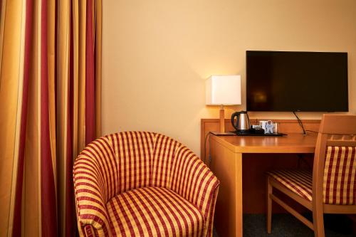 a hotel room with a chair and a desk with a television at Hotel Schwertfirm in Karlsfeld