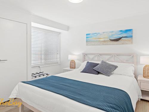 a white bedroom with a bed and a window at Waves on Whitesands in Fingal Bay