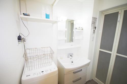 uma casa de banho com um lavatório e uma máquina de lavar roupa em ラ・ルーチェ東仲宗根 em Miyako Island