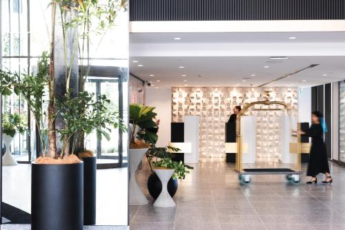 a lobby with potted plants and people in the lobby at Hotel X Brisbane Fortitude Vly, Vignette Collection by IHG in Brisbane