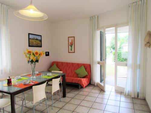 un soggiorno con tavolo e divano rosso di The perfect family retreat - Beahost a Bibione