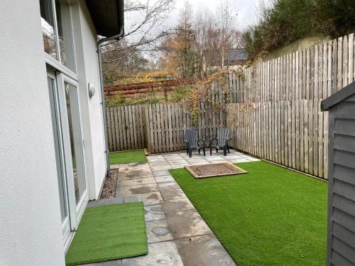 a patio with green grass next to a fence at Woodside retreat holiday home in Aviemore in Aviemore