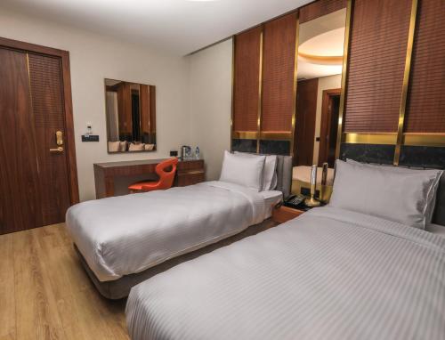 a hotel room with two beds and a red chair at Henna Hotel Istanbul in Istanbul