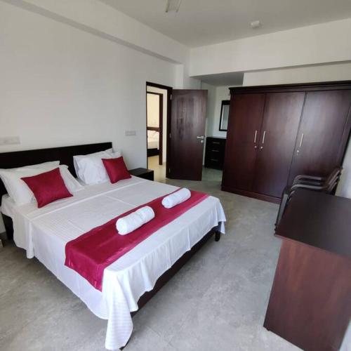 Modern apartment in close proximity to the Beach في كولومبو: غرفة نوم بسرير كبير ومخدات حمراء وبيضاء