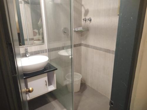 a bathroom with a glass shower and a sink at Zip By Spree Hotels Surabi International Vellore in Vellore